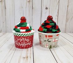 two christmas cupcakes decorated with red and green frosting sitting on top of a wooden table