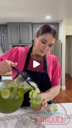 a woman in an apron is making a drink with cucumbers and limes