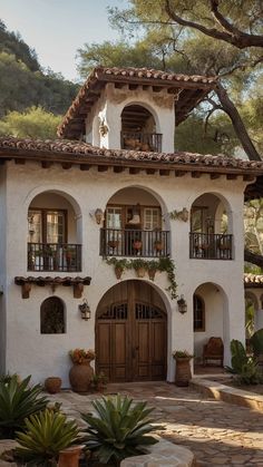 a white stucco house with brown doors and plants in the front yard, on a sunny day