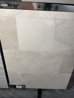 a white marble counter top sitting on top of a wooden floor next to a tiled wall