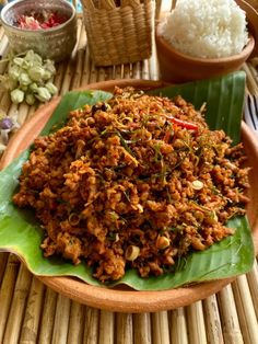 a plate filled with rice and meat on top of a wooden table next to other food items