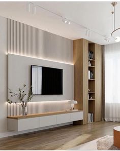 a modern living room with white walls and wooden flooring, built in bookshelves