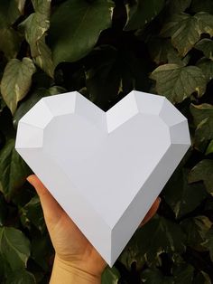 someone holding up a white heart shaped box