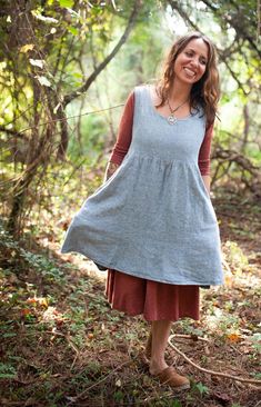 a woman standing in the woods wearing a dress