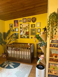 a baby's room with yellow walls and pictures on the wall, including a crib