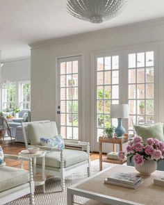 a living room filled with lots of furniture and flowers on top of a coffee table