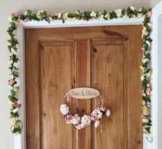 a wooden door decorated with flowers and greenery