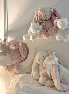 three stuffed animals sitting on top of a bed next to each other in a room