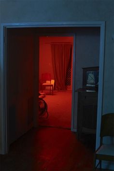 an open door leading to a bedroom with red light coming in from the closet area