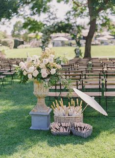 an arrangement of flowers and umbrellas on the grass at a wedding ceremony with rows of chairs in the background