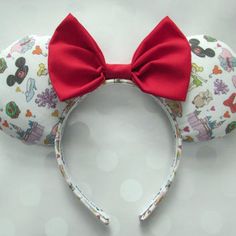 a minnie mouse ears headband with red bow on it's side and disney characters all over the band