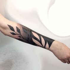 a man's arm with black leaves on it