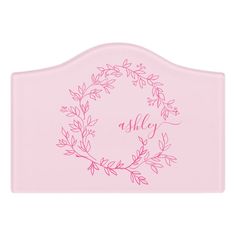 a pink bed headboard with a wreath on the top and name written on it