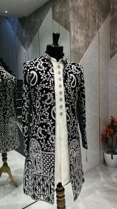 a black and white jacket on display in front of a marble wall with an ornate design