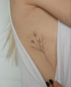 a woman's stomach with a small flower tattoo on her left side ribcage