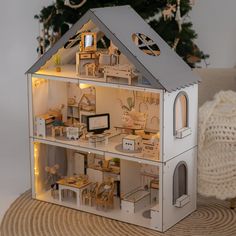 a doll house with furniture and christmas tree in the backgroung, it's all lit up