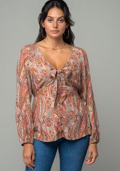 A sweet tie-front top designed in a vintage-inspired paisley print. Paisley print Relaxed fit Long voluminous sleeve Elastic wrist cuff Plunging v-neckline Button front Tie front detail Half elastic waist in back Bohemian top A bohemian paisley print adds a retro touch to this classic blouse. Featuring voluminous long sleeves, a button front, and a flirty v-neckline with a tie front detail. An effortless style for summer or fall, we love to pair it with vintage denim. Model is 5'8, wearing a siz Fall Paisley Print V-neck Blouse, Fall V-neck Blouse With Paisley Print, Chic V-neck Tops With Paisley Print, Chic V-neck Paisley Print Tops, Feminine V-neck Tops With Tie Sleeves, Feminine V-neck Blouse With Tie Sleeves, Volume Sleeves, Classic Blouse, Bohemian Top