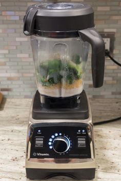 a blender filled with liquid and vegetables on top of a kitchen counter next to a tile backsplash