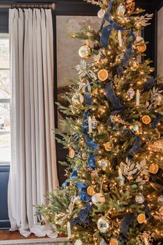 a decorated christmas tree with blue and gold ornaments on it in front of a window