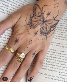 a woman's hand with a butterfly tattoo on it, and an open book