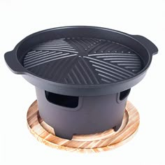 the grill is on top of a wooden stand with an empty pot in front of it