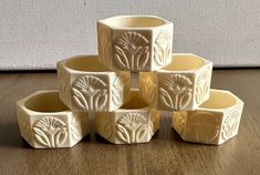 six white vases sitting on top of a wooden table