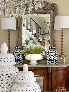 a room with a mirror, vases and chandelier on the side table