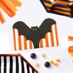 some candy sticks and halloween decorations on a white table with black and orange striped napkins