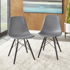 two gray chairs sitting on top of a white rug next to a potted plant