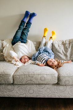 two children laying on a couch with their feet up in the air and one lying down