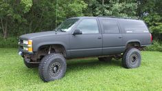 a large gray truck parked on top of a lush green field