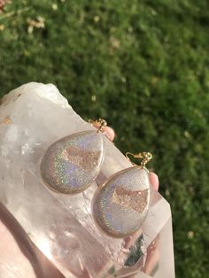 These holographic Teardrop geode earrings made from resin shift from clear gold to a beautiful sparkly rainbow. They are lightweight and won't bother your ears. Please be aware that resin is heat resistant up to 135 degrees. Wearing these earrings in extremely hot temperatures will cause them to be pliable. If this happens, simply place in a cooler location. I am not responsible for any damaged earrings due to extreme heat. Made by Katie Glover Resin Art by Katie 2020 Contact me on my Instagram Unique Iridescent Teardrop Earrings, Clear Resin Jewelry With Ear Wire, Teardrop Resin Jewelry, Iridescent Sparkling Jewelry As Gift, Iridescent Sparkling Jewelry Gift, Sparkling Iridescent Jewelry As Gift, Sparkling Iridescent Jewelry For Gifts, Iridescent Drop Earrings For Gift, Iridescent Glitter Earrings As Gift