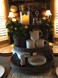 a stack of coffee cups sitting on top of a table next to plates and bowls