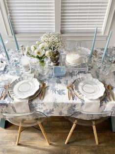 the table is set with blue and white china plates, silverware, and flowers