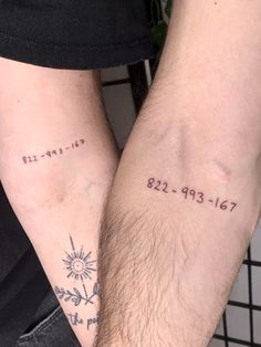 two people with matching tattoos on their arms, one is holding the other's arm