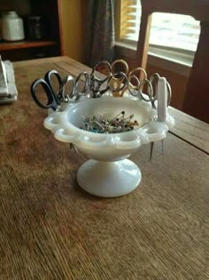 a white bowl filled with scissors on top of a wooden table