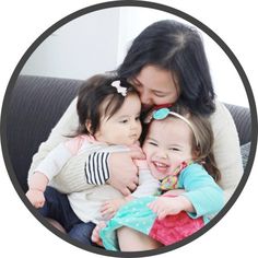 a woman holding two small children on top of a couch in front of a black and white circle