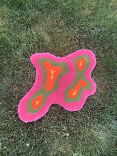 a pink and green rug sitting in the grass