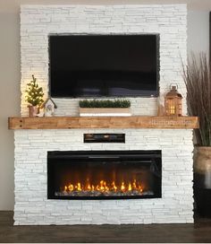 a fireplace with a flat screen tv mounted above it and lit candles on the mantle