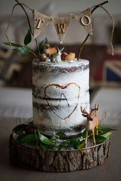 a wedding cake decorated with deer figurines and bunting on a tree stump