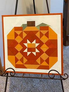 an orange and white pumpkin quilt hanging on a stand