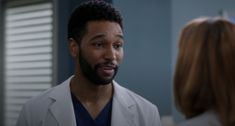 a man in a lab coat talking to a woman who is looking at him and smiling