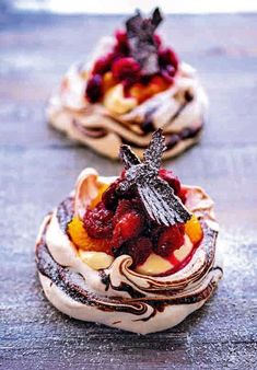 three desserts with fruit on top are sitting on the table