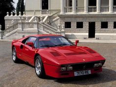 a red sports car parked in front of a white building with steps leading up to it