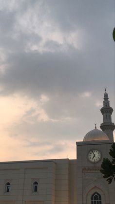 a large white building with a clock on it's face in front of a cloudy sky