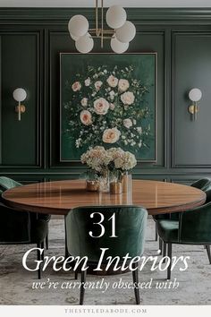 a dining room with green chairs and a round wooden table in front of a painting