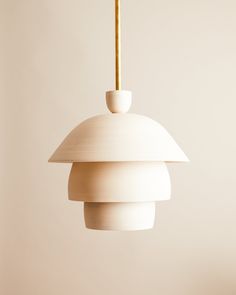 a white light hanging from a ceiling fixture with a wooden stick sticking out of it