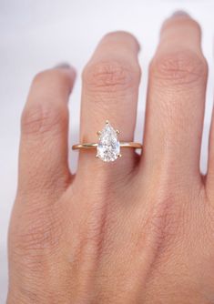 a woman's hand with a gold ring and a white diamond in the middle