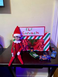 an elf is sitting on top of a desk with candy bars and a sign that says elf caravan