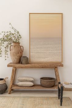 a wooden shelf with a vase and other items on it in front of a white wall